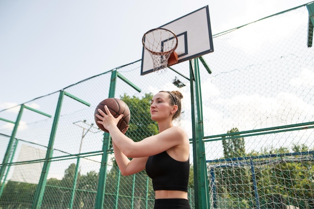 Atletische vrouwelijke basketbalspeler die een bal naar het net gooit