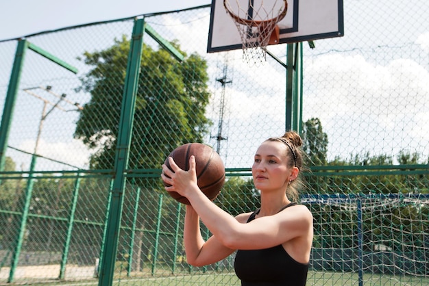 Atletische vrouwelijke basketbalspeler die een bal naar het net gooit