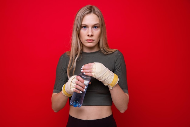 Atletische vrouwelijke bokser drinkt water op rode achtergrond