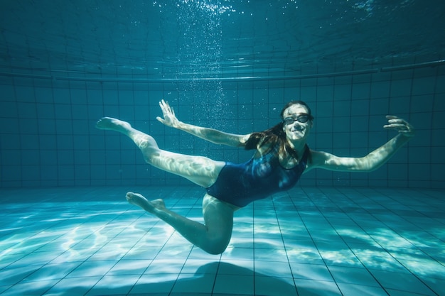 Atletische zwemmer die bij camera onderwater glimlachen