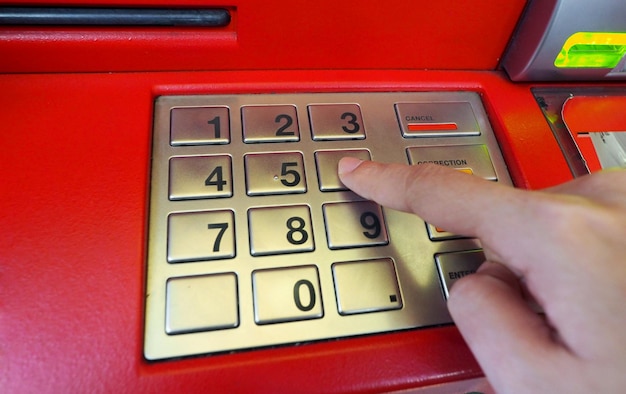 ATM-machine rode kleur en vinger met de hand op de nummerknop voor opname en close-up shot.