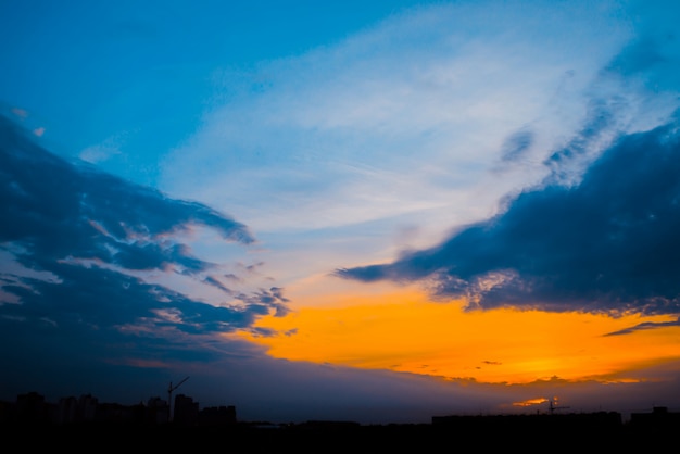 Atmosferische blauwe bewolkte hemel achter silhouetten van stadsgebouwen