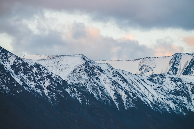 Atmospheric alpine landscape to snowy mountain ridge in sunset.