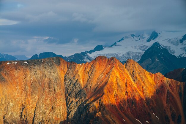 Atmosferico paesaggio alpino con montagne rocciose rosse nell'ora d'oro.