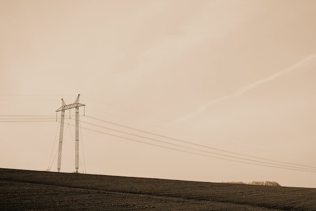 Atmospheric landscape with power lines in field