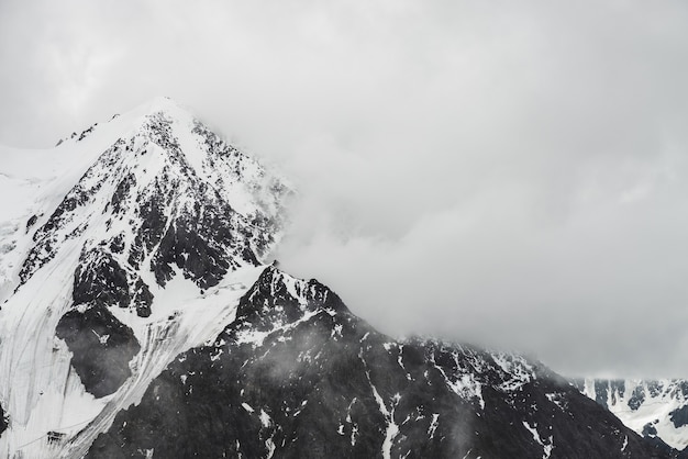 Atmospheric minimalist alpine landscape with massive hanging glacier on snowy mountain peak.