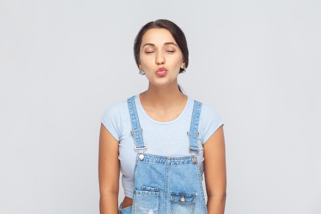 Atractive beautiful woman wearing denim overalls standing with closed eyes expressing love and