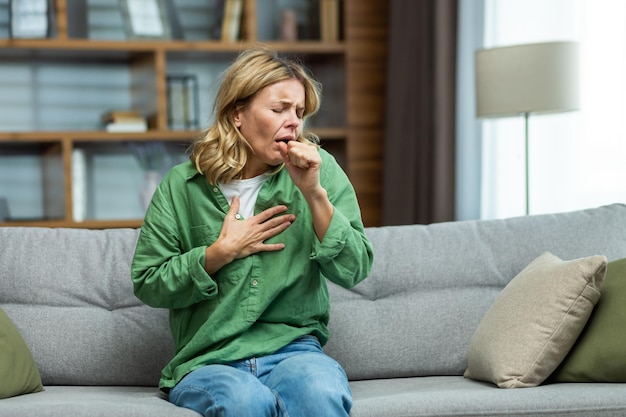 Foto un attacco di allergie asmatiche a casa una donna anziana è seduta sul divano tenendosi il petto e