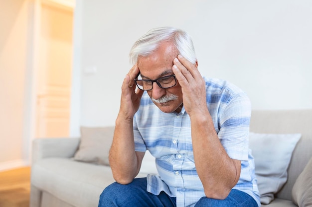 Атака чудовищной мигрени несчастный пенсионер пожилой человек держит голову с выражением боли лицо пожилого человека страдает от головной боли