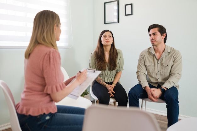 attending couples therapy. young woman and man sitting and talking with a female psychologist about the problems in their marriage