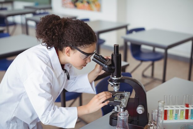 Attent schoolmeisje kijkt door Microscoop in laboratorium