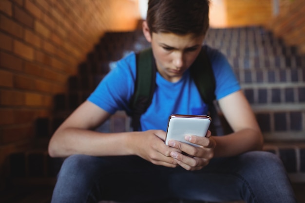 Attente schooljongen met behulp van mobiele telefoon op trap