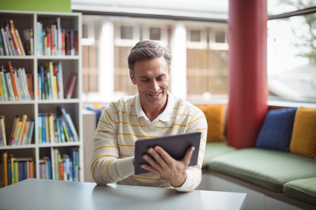 Foto attente schoolleraar met behulp van digitale tablet in bibliotheek