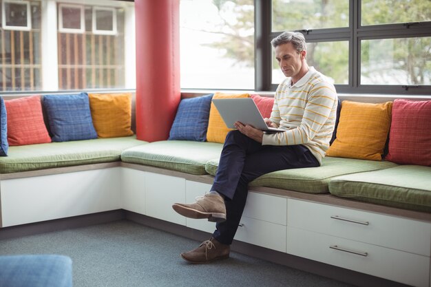 Attente schoolleraar met behulp van laptop in bibliotheek