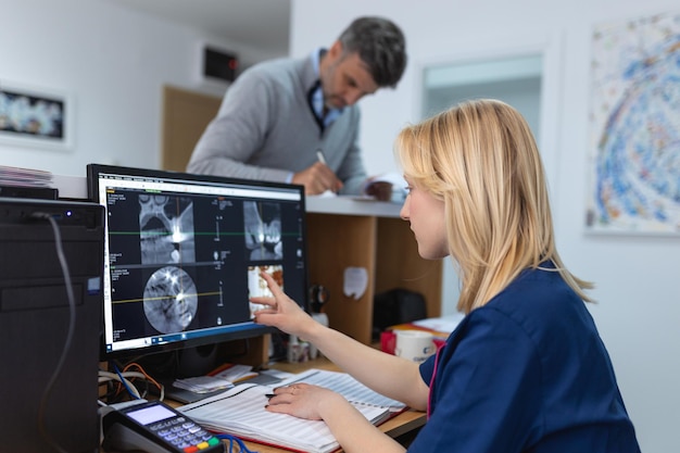 Foto attente tandarts die een röntgenfoto op de computer in de tandheelkundige kliniek onderzoekt