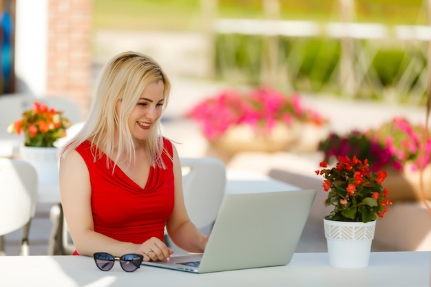 Attente vrouw die naar media kijkt in een laptop in een coffeeshop op het zomerterras op de achtergrond