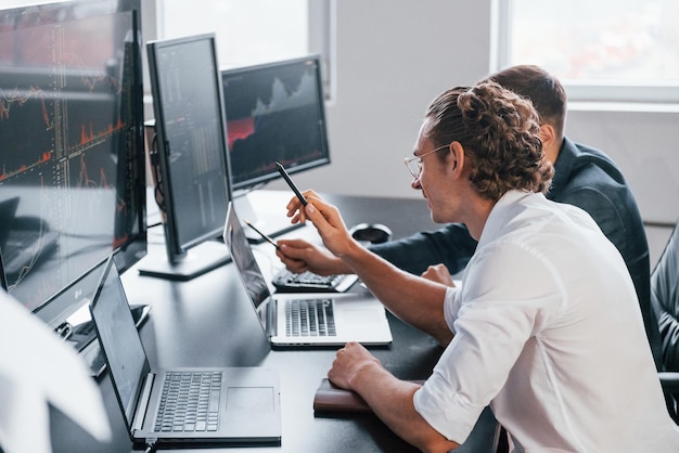 attention to details team of stockbrokers works in modern office with many display screens