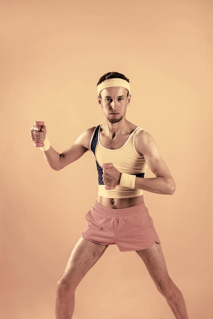 Attention start finish workout close up portrait of crazy youth\
man pulling small pink dumbbells isolated on shine yellow\
background