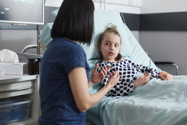 Attentive careful kind young mother talking with ill daughter while offering emotional support. Considerate woman and relaxed child talking together about treatment and recovery period time.