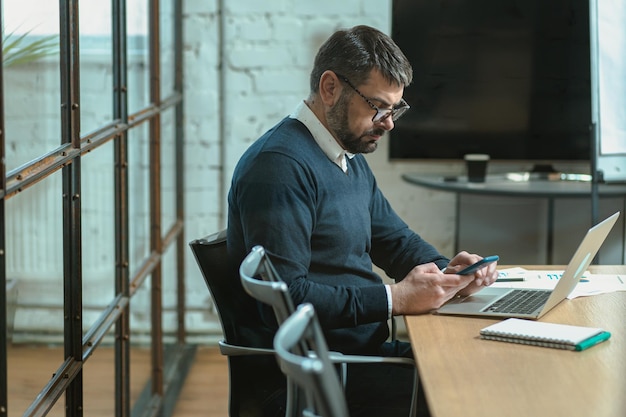 Attentive Caucasian man using smartphone while reading message