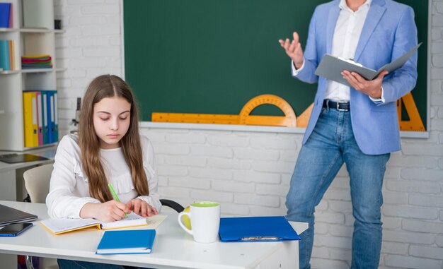 Attentive child study in classroom with teacher selective focus