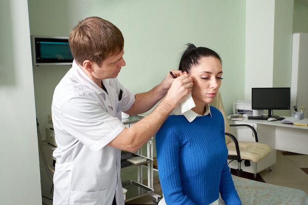 Attentive ent doctor doing ear exam of pretty woman