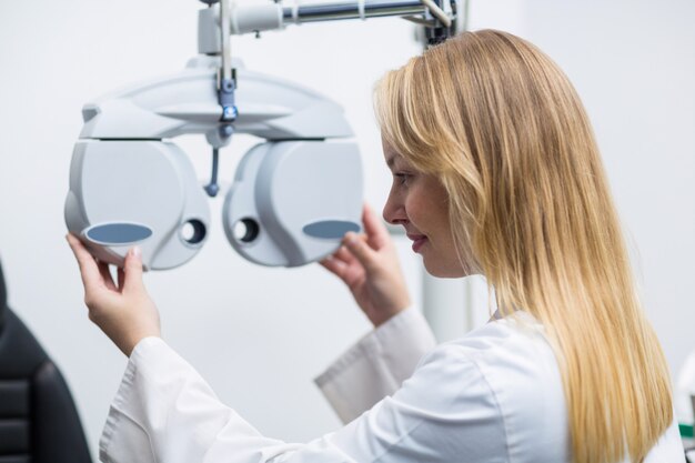 Attentive female optometrist adjusting phoropter