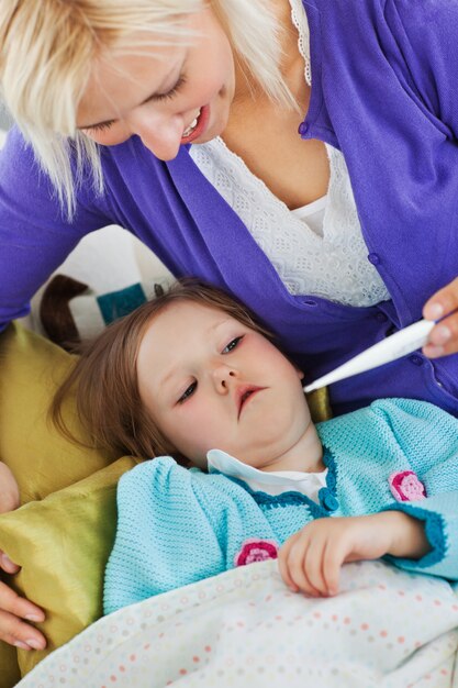 Attentive mother takes her daughter's temperature 