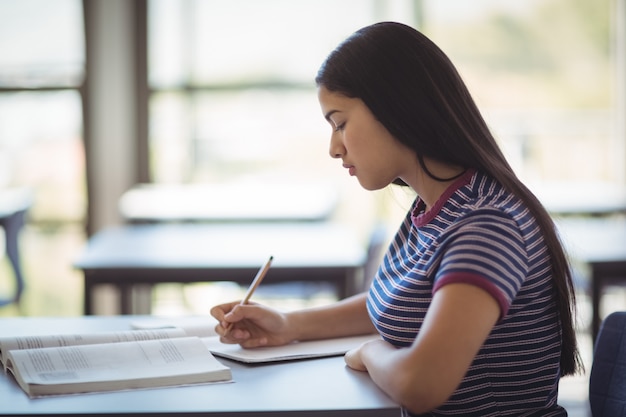 Photo attentive schoolgirl studying in classroom