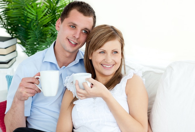 Attentive young couple drinking coffe sitting on a sofa in the livingroom