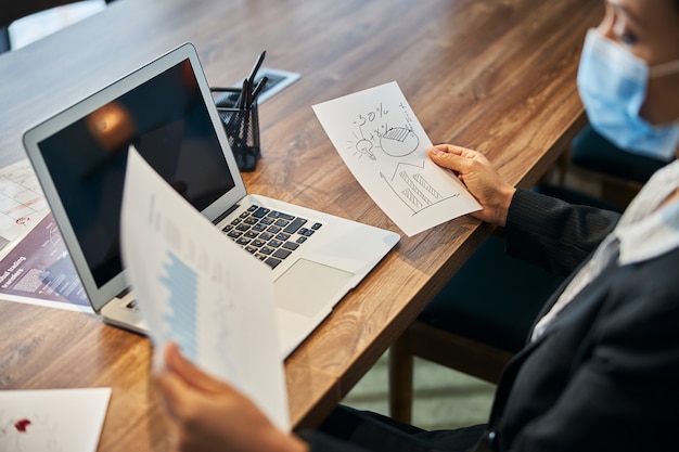 Attentive young worker sitting in semi position in front of her laptop while controlling profit