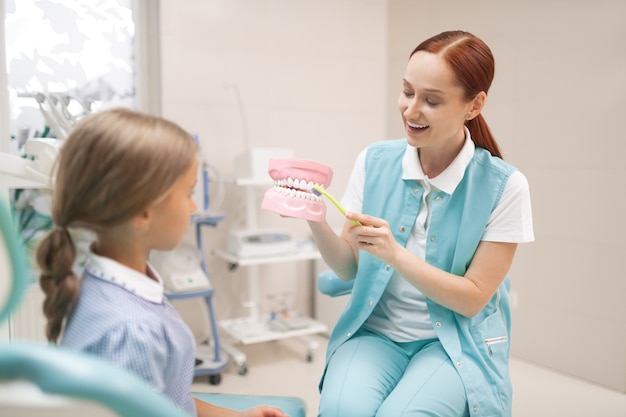 Attentively listening. Girl attentively listening to dentist teaching her to brush teeth properly twice a day