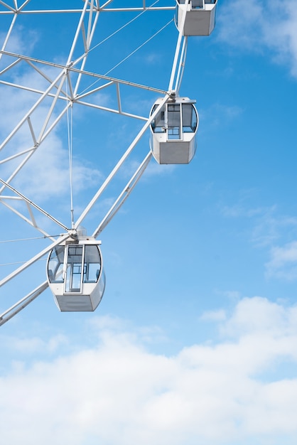 Attraction Ferris wheel in the park of the cloudy sky. Vertical photo