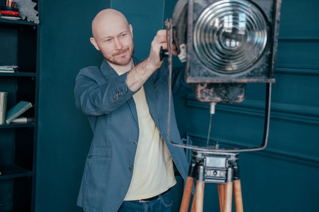 Attractive adult bald man with beard in suit looking at old lighting fixture, video light