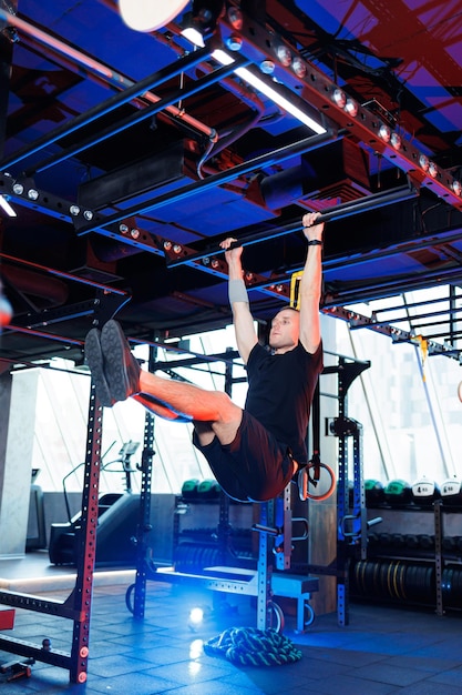 Attractive adult man doing exercises and lifting weights in the gym. Sports training in the gym