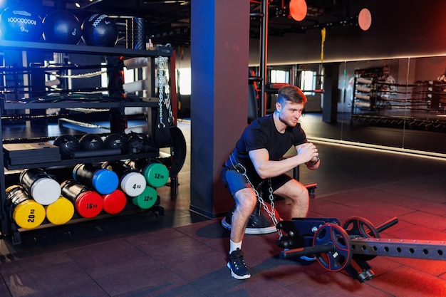 Attractive adult man doing exercises and lifting weights in the gym. Sports training in the gym