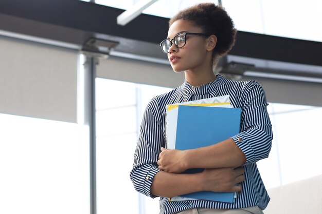 Attractive african american business woman smiling while standing in the office.