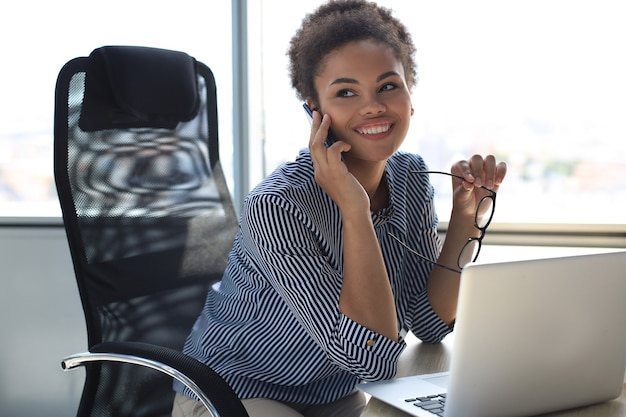 Attractive african american business woman talking with collegues on the mobile phone.