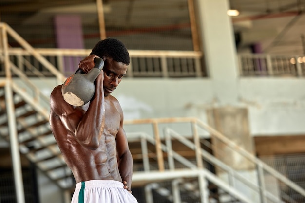 Attractive african american man smiling and doing exercise with dumbbells