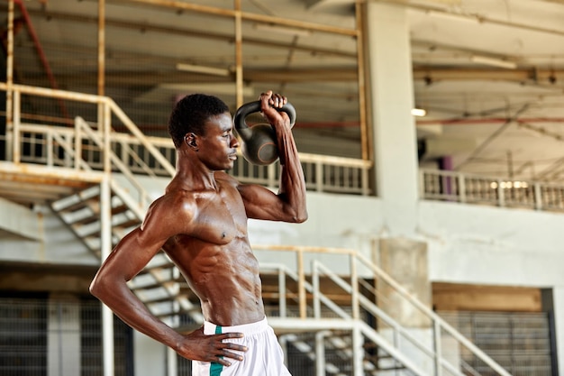 Attraente uomo afroamericano sorridente e facendo esercizio con manubri