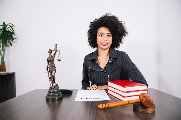 Attraente donna afroamericana al tavolo con libri, documenti e figure