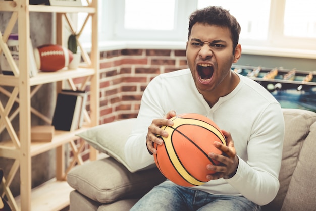 Attractive Afro American man is holding a basketball ball.