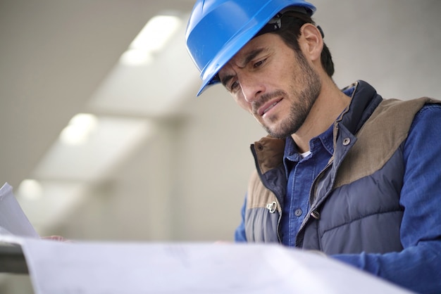 Attractive architect in hardhat checking blueprints outdoors