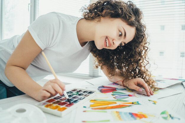 The attractive artist painting a picture at the table