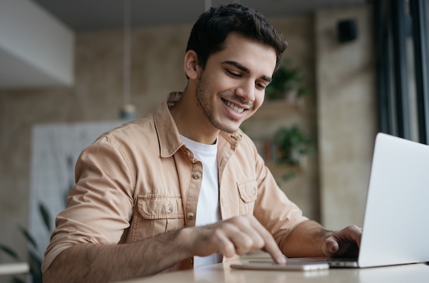 Attractive asian businessman using laptop and smartphone, working start up project in office