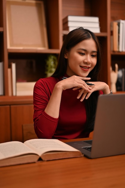 Donna d'affari asiatica attraente o consulente femminile che utilizza il computer portatile che esamina lo schermo del computer portatile