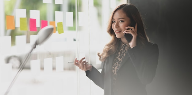 Attractive Asian businesswoman speaking on the phone with her customer 