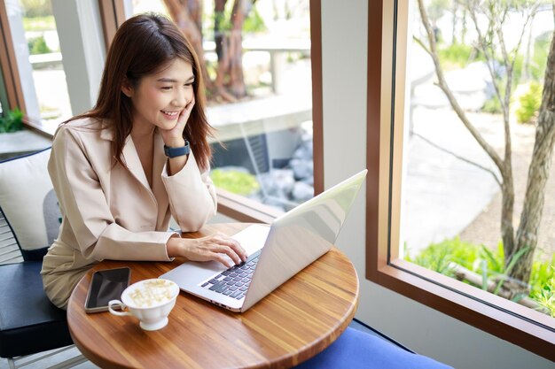 커피숍에서 노트북으로 일하는 매력적인 아시아 여성 자신감 있고 똑똑한 여성 및 비즈니스 개념