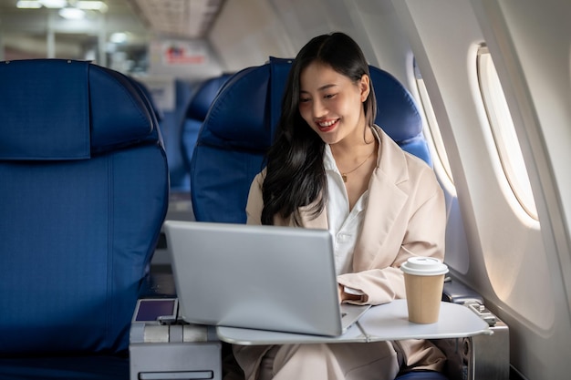 An attractive Asian female CEO is working on her laptop during the flight for her business trip