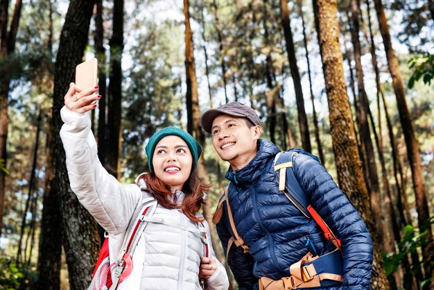 Attractive asian hikers couple taking selfie photo with mobile phone